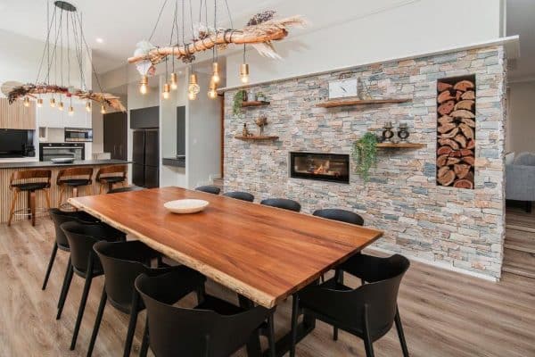 a home with a dining table and natural ledge cladding on the walls